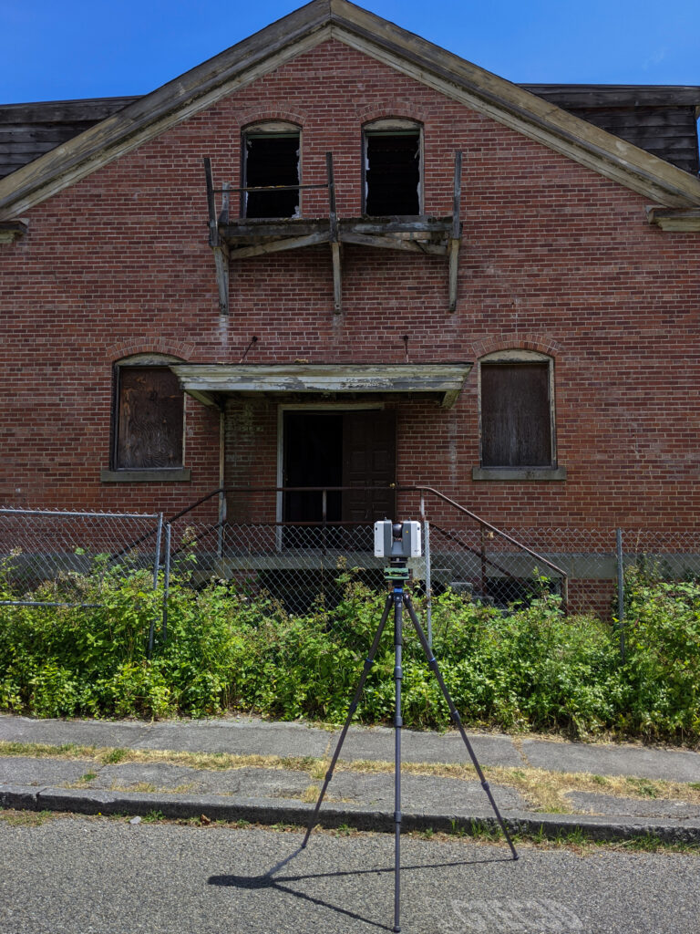 A GTEC3D technician operates a Leica RTC360 3D laser scanner to capture data from the exterior of the historic "Station S" naval listening station building at Fort Ward, Washington.