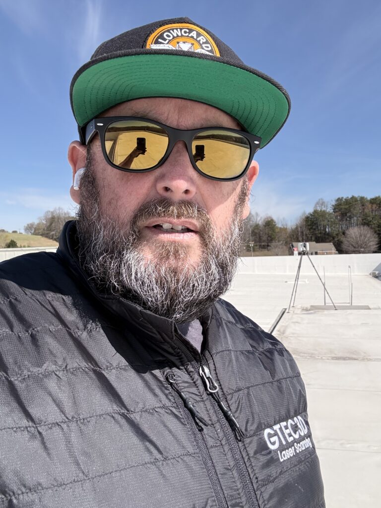 A GTEC3D technician wearing a branded high-visibility safety vest operates a Leica RTC360 laser scanner during a site survey at the old Lowe’s Head Office in North Carolina.